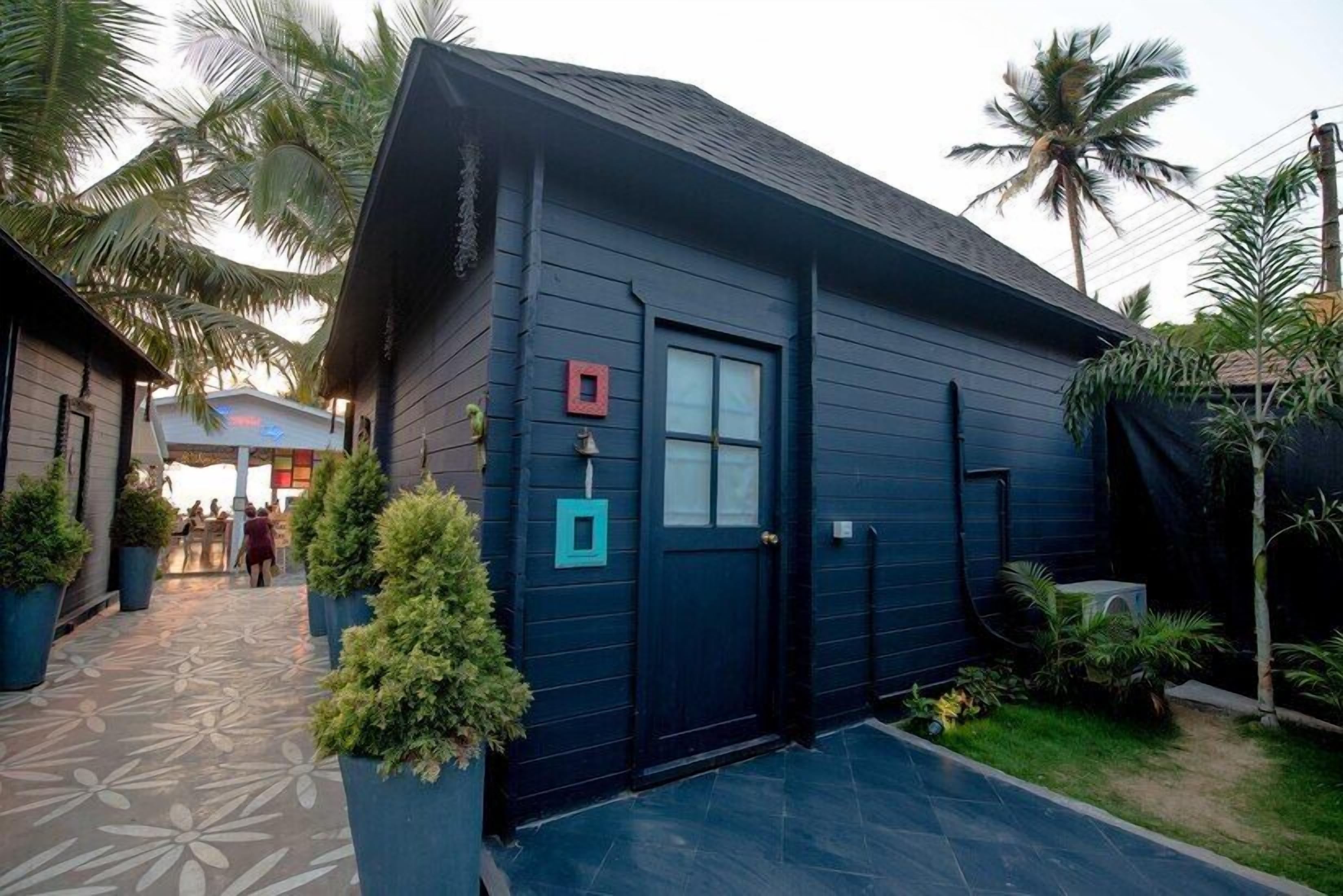 A dark blue building with a tiled entrance and a small garden area with potted plants.