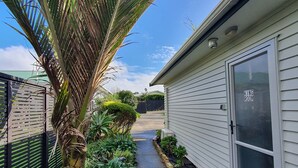 A pathway leading to a house with a 'KING ROOM' sign, surrounded by lush greenery and a palm tree.