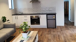 A modern kitchen with white cabinets, a stainless steel range hood, and a built-in oven.