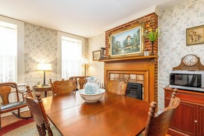 Traditional dining room with a long table and ornate chairs, fireplace, and decorative wall art.