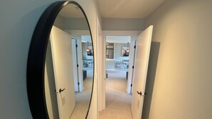A hallway with a large mirror on the left, leading to a dining area with a high chair and a hanging light fixture. - Renovated Whistler Village Condo with Stunning Blackcomb Views (Whistler)