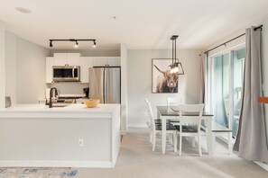 A modern kitchen with white cabinetry, a built-in microwave, and a stainless steel range hood.