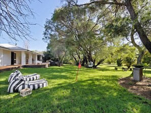A grassy backyard with a house, a swing set, and a red flag.