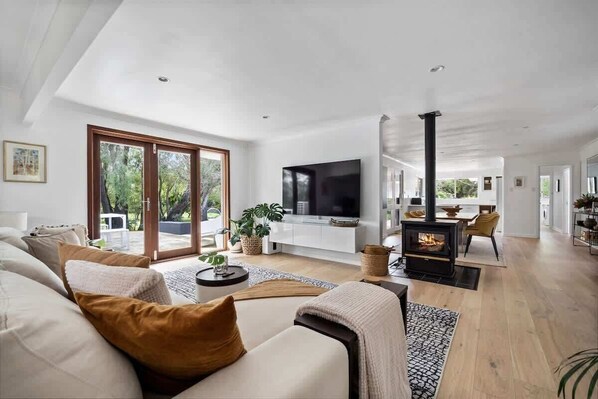 Una sala de estar moderna con sofá, televisión, chimenea y vistas al exterior.