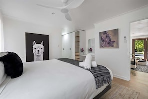 Un dormitorio con una cama grande, un ventilador de techo, un armario y un cuadro en la pared.