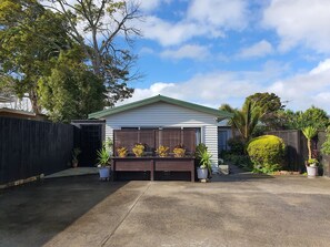 A garage with a green roof, surrounded by potted plants and a wooden fence.