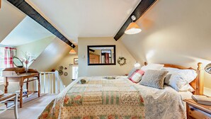 Un dormitorio cálido en el ático con una cama grande, un escritorio de madera y un espejo.