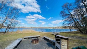 Un espace de pique-nique au bord du lac, équipé de bancs, d’un foyer et d’un abri en bois.