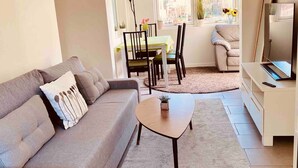 Un salon comprenant un canapé, une table basse et un meuble pour la télévision. On y trouve également un coin repas avec des chaises et une table.