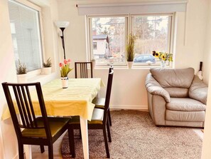 Un comedor con una mesa, sillas, un sofá y una ventana con plantas.