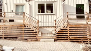Un bâtiment blanc avec un toit en tuiles, une entrée centrale dotée d’un petit porche et une porte verte.