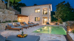 A modern house with a swimming pool, stone walls, and outdoor seating. - Prenari Villa in Paxi (Paxos)