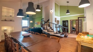 Uma sala de estar espaçosa com uma mesa de jantar de madeira, várias cadeiras e uma escada que leva a um andar superior.