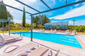 A swimming pool with lounge chairs and a covered area with a glass structure. - Villa La Pieve in Citt Della Pieve (Citta della Pieve)