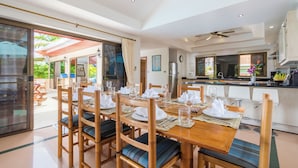 A dining area with a wooden table set for four, surrounded by chairs with cushioned seats.
