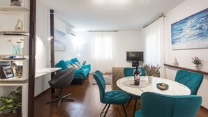 A modern living room with teal chairs, a white dining table, and a TV on a stand. - Top Location Beach & Downtown Split Apartment Park (Split)