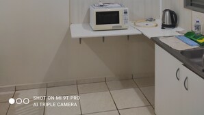 A compact kitchen with a microwave, kettle, and a small sink.