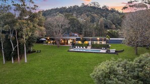 A modern house with a swimming pool, surrounded by a well-maintained lawn and trees.