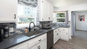 Une cuisine moderne avec des meubles blancs, un lave-vaisselle, un four à micro-ondes et un évier.