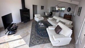 Una sala de estar moderna con chimenea, sofás blancos, una mesa de centro y una televisión.