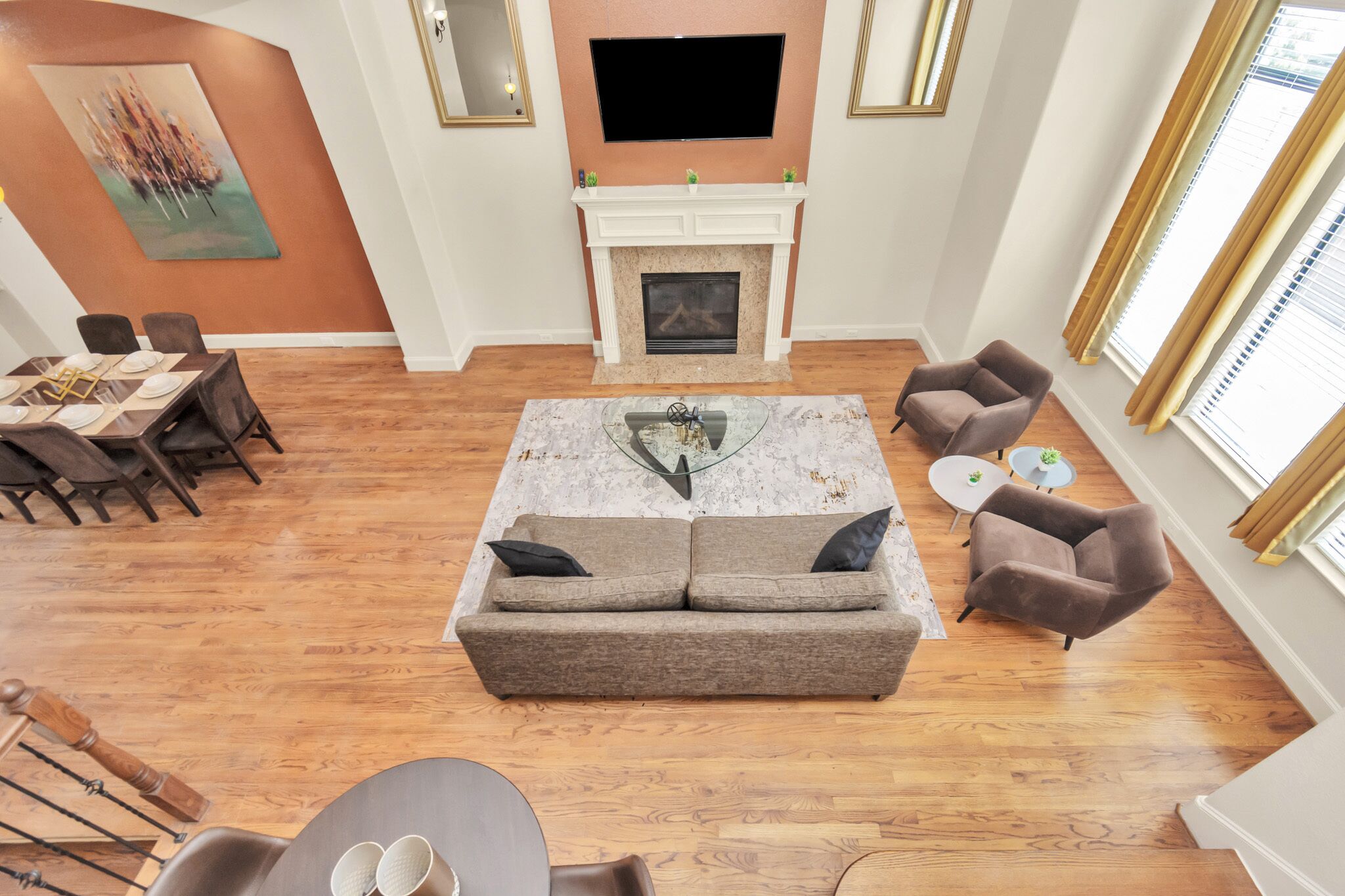 A living room with a fireplace, a sofa, a dining table set, and a TV mounted on the wall.