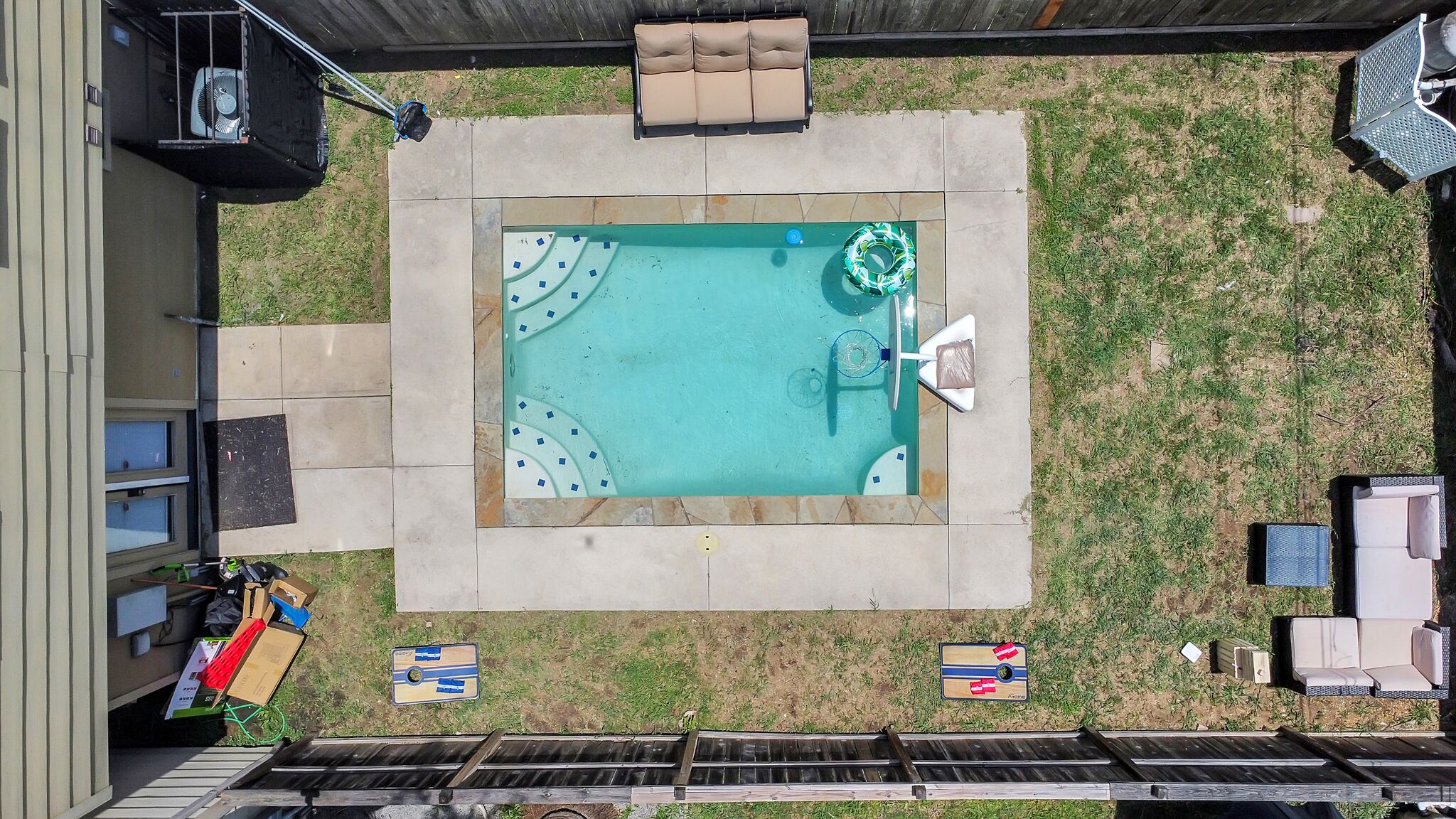 A rectangular swimming pool with a surrounding deck, a lounge chair, and a small table.
