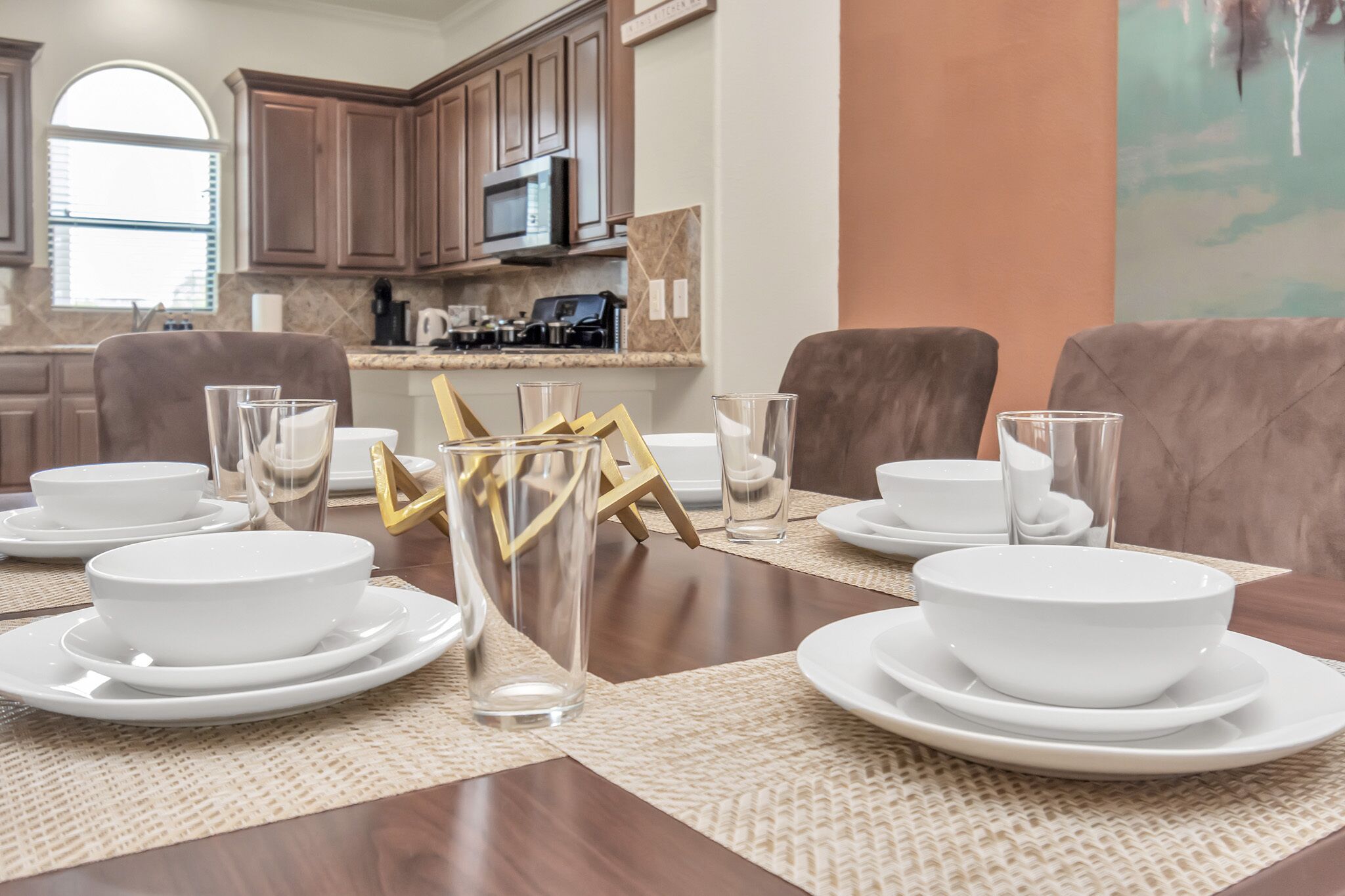 Un comedor con una mesa de madera dispuesta para cuatro personas, rodeado de sillas.