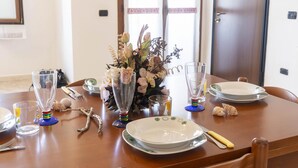 A dining table set with plates, cutlery, and a vase of flowers. - Casa Su Lizu in Tanaunella (Budoni)
