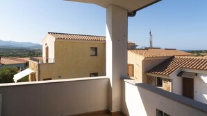 A balcony with a view of neighboring buildings and a distant tower. - Casa Su Lizu in Tanaunella (Budoni)