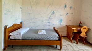 A single bed with a wooden headboard, a small wooden desk with a chair, and a wall with blue paint splatters. - Rustico D Amare in Quartu Santa Elena (Quartu Sant'Elena)