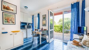 A bright room with a kitchen, dining area, and a sofa with a TV. - Gli Oleandri di Procchio (Procchio)