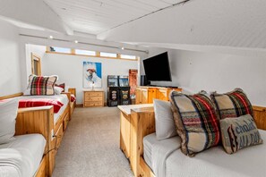 A cozy room with wooden furniture, a flat-screen TV, and a gaming console. - Ski In/Walk Out, Hot Tub, Epic Views, W/D, & Games (Steamboat Springs)