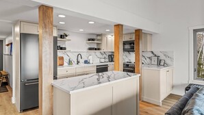 Cozinha moderna com bancadas de mármore, vigas de madeira e uma ilha central.