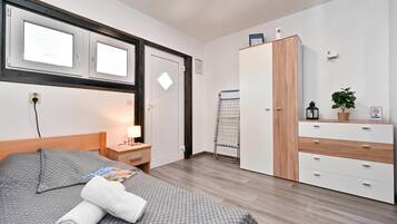 A hotel room with a bed, a nightstand, a wardrobe, a window, and a door.