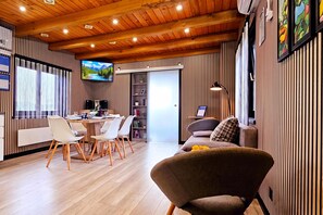 A modern interior with a dining area, a sofa, and a TV mounted on the wall. - AquaHaven With Private Pool And Wellness (Veliko Trgovisce)