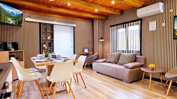 Un salon moderne comprenant un coin repas, un plancher en bois et une grande fenêtre avec des rideaux.