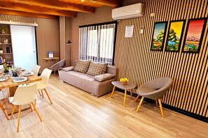 A modern living room with a sofa, dining table, chairs, and a small side table with flowers. - AquaHaven With Private Pool And Wellness (Veliko Trgovisce)