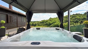 A hot tub under a canopy with a view of a house and greenery. - AquaHaven With Private Pool And Wellness (Veliko Trgovisce)