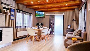 A modern interior with a dining area, a sofa, and a TV mounted on the wall.