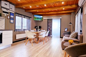 A modern interior with a dining area, a sofa, and a TV mounted on the wall. - AquaHaven With Private Pool And Wellness (Veliko Trgovisce)