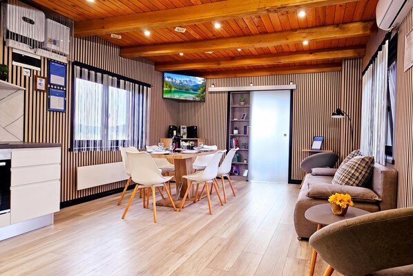 Un interior moderno con comedor, sofá y televisor montado en la pared.