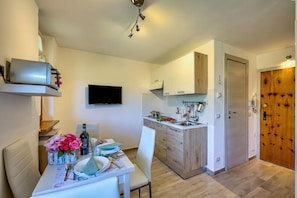 A modern kitchen with white cabinets, a built-in oven, and a dining area with a table set for two. - Studio La Borracina Mountain View (Sauze d'Oulx)