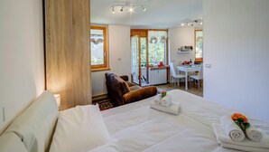 A hotel room with a bed, a wooden wardrobe, a desk with a chair, and a view through the window. - Studio La Borracina Mountain View (Sauze d'Oulx)