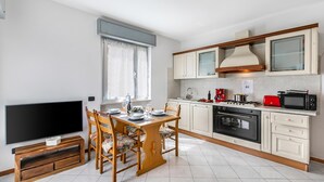 A modern kitchen with a dining area, a flat-screen TV, and a built-in oven.