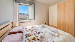 A bedroom with a bed, a window, a radiator, and wooden wardrobe.
