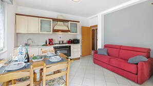 A compact living space with a kitchen, dining area, and a red sofa.