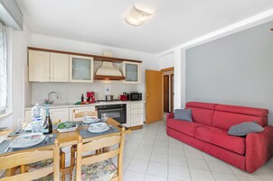A compact living space with a kitchen, dining area, and a red sofa.