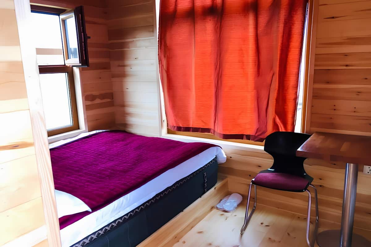 A compact room with a bed, a small table, and a chair.