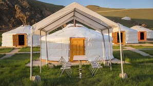 A series of yurts with a central tent-like structure, each with a wooden door and surrounded by grass. - Ulaanbaatar (Erdene)