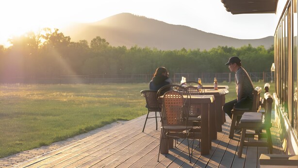 A wooden deck with outdoor seating, overlooking a grassy field and a mountain in the background. - Ulaanbaatar (Erdene)